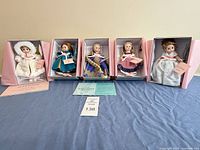 Five dolls in open boxes with paperwork displayed
