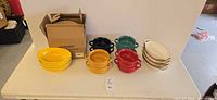 full lot showing yellow bowls, handled bowls in multiple colors, oval dishes, and Hasense box