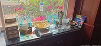 Full view of lot on countertop including boxed coasters, goblets, bowls, dishes, figurine and art