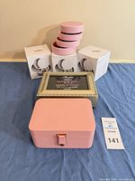 All items together: pink travel case, gold music/photo box, four round pink cases and retail boxes