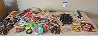 Overview of all tackle spread on table including reels, plastics, hard baits, terminal tackle, gloves