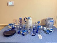 Full lot showing glasses, plates, pitcher, candlestick, bowls and urn on table