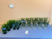 Entire lot of green glass tumblers and goblets displayed on table