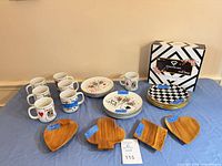 All items laid out: mugs, playing-card plates, checkered plates, wooden bowls, box