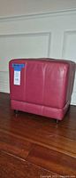 Front side view of red cube ottoman showing stitched panels and feet