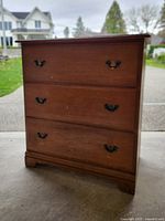 Front view of 3-drawer wooden chest with brass-tone pulls