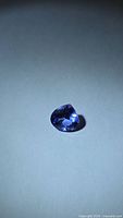 Pear-cut violet-blue tanzanite gemstone on neutral background