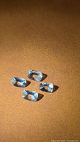 Four cushion-cut pale blue aquamarines on brown background