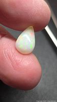 Opal showing play of color held between fingers