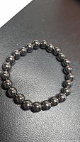 Circular stretch bracelet of polished dark metallic hematite beads