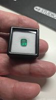 Emerald in display box held between fingers