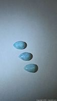 Three pear-shaped larimar cabochons on neutral background