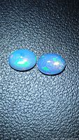 Two oval cabochon Ethiopian opals side by side showing blue body colour and multicolour flashes