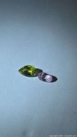 pear-cut green and oval pink tourmalines on neutral background