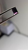 Baguette purple spinel in tweezers, showing table and crown