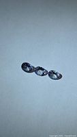 Three oval bluish-violet faceted stones on neutral background
