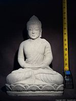 Front view of cement Buddha statue with tape measure for scale