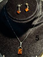 Front view of pendant necklace and earrings showing amber stones and silver settings