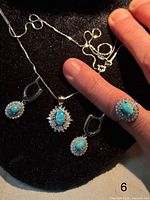 Front view of ring, pendant on chain, and pair of earrings showing turquoise cabochons and zirconia halos