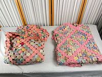 Two folded yo-yo patchwork bedspreads side by side on table