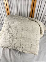 Folded beige eyelet comforter on bed showing exterior pattern