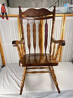 Front view showing spindle back, carved crest and arms