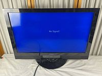 Front view of Vizio SV320XVT TV displaying blue screen with 'No Signal' message