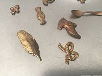 Feather, bow, shoe, floral urn, spoon, fleur-de-lis shown