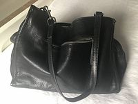 Full view of black leather shoulder bag showing exterior texture and strap