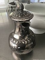 Full view of silver-plated coffee pot showing lid, finial and body