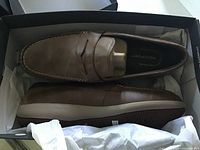 Top view of both brown leather loafers inside original box
