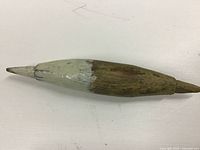 Side view of full wooden bobber showing white paint and natural wood