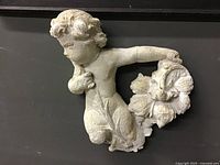 Front view of chalkware cherub wall relief