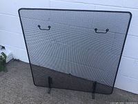 Front view of entire wire mesh fireplace screen showing mesh panel, brass-tone handles, and feet