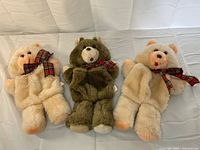 front view of three teddy bear plush stockings showing colors, bows, and design