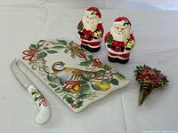 Cheese board, knife, pair Santa shakers and wine stopper grouped on table