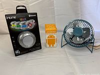 Group shot of iHome speaker box, Android figure box, and blue USB fan