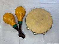 Pair of yellow maracas and skin-head tambourine on white cloth