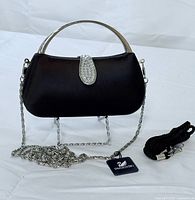 Front view of black satin Swarovski evening bag with crystal clasp, chain strap and tag