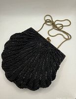 Front view of black beaded clamshell bag with chain displayed