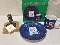 Full lot view showing plate, mug, cookie press, Santa’s Snack Set box