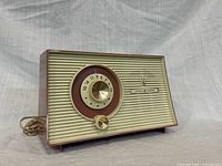 Front left view of GE T-102A radio showing grille, tuning dial, volume knob and cord