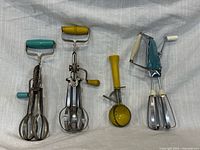 Front view of all four vintage kitchen tools upright