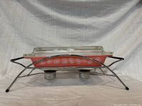 Side view of casserole in chrome cradle showing Pink Daisy pattern and candle holders