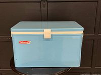 Front view of blue Coleman metal cooler with latch and logo