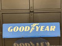Front of blue metal Goodyear sign resting horizontally