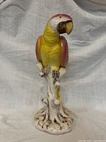 Full view of porcelain parrot statue on stump