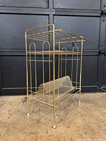 Angled view of brass-tone record player stand showing overall design and condition