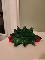 front view of green ceramic holly leaf napkin holder with red berries