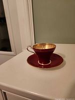 Teacup on saucer showing burgundy exterior, gold interior